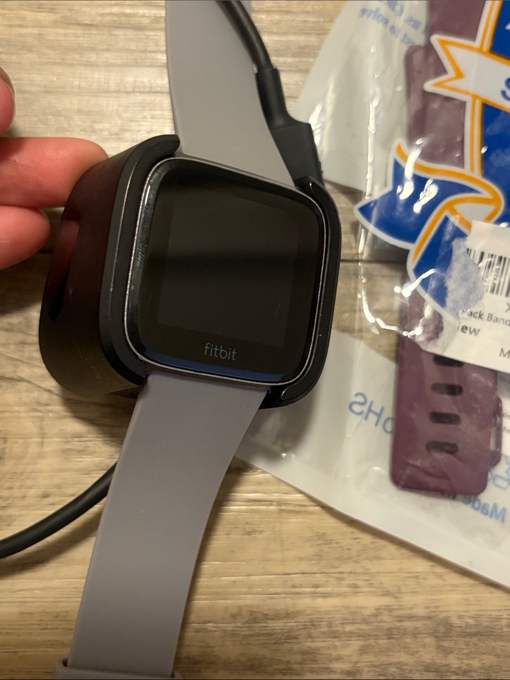 fitbit versa gen 1 smartwatch with gray band and black charger
